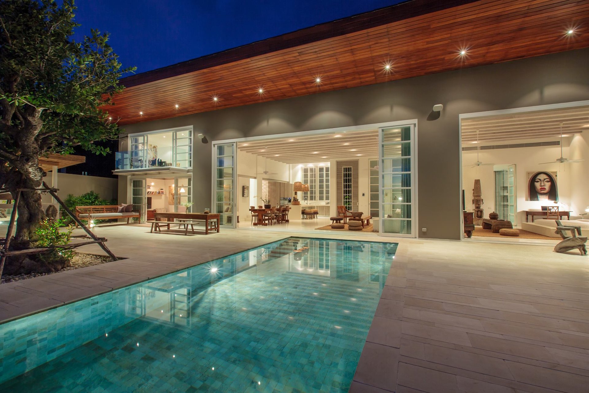 Open tropical villa living space overlooking a pool at night